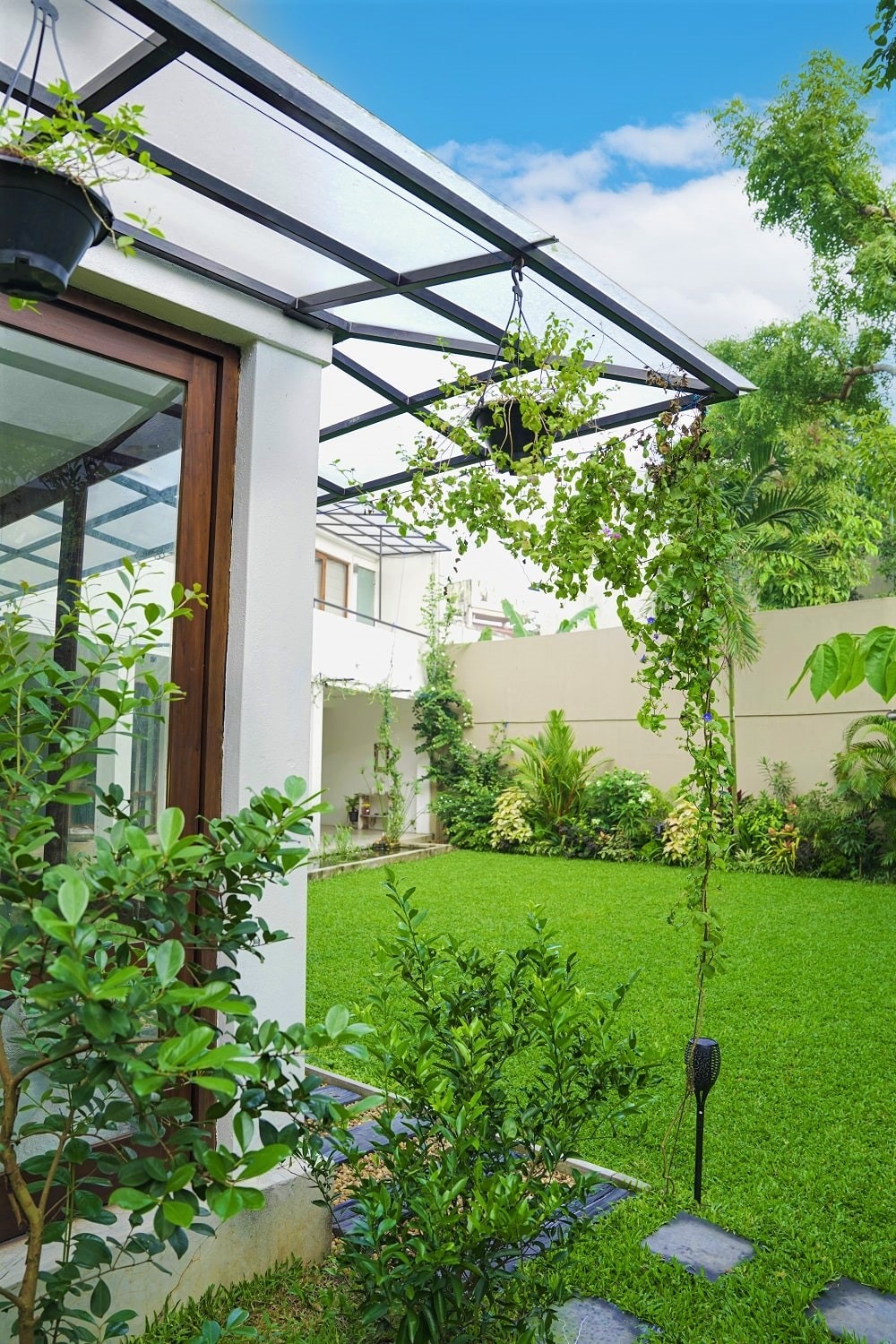Home garden with big trees, bushes, hanging plants and a lawn