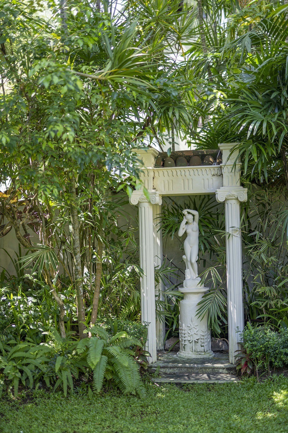 A garden view a lawn, large trees, bushes and garden sculpture